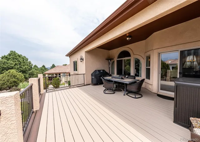 a view of a roof deck with table and chairs a barbeque with wooden floor and fence