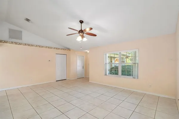 a view of an empty room and chandelier fan
