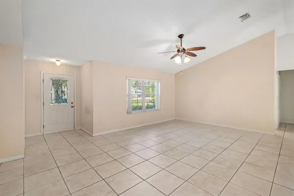 a view of an empty room and chandelier fan