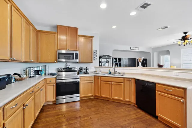 a kitchen with stainless steel appliances granite countertop a sink stove and wooden floor