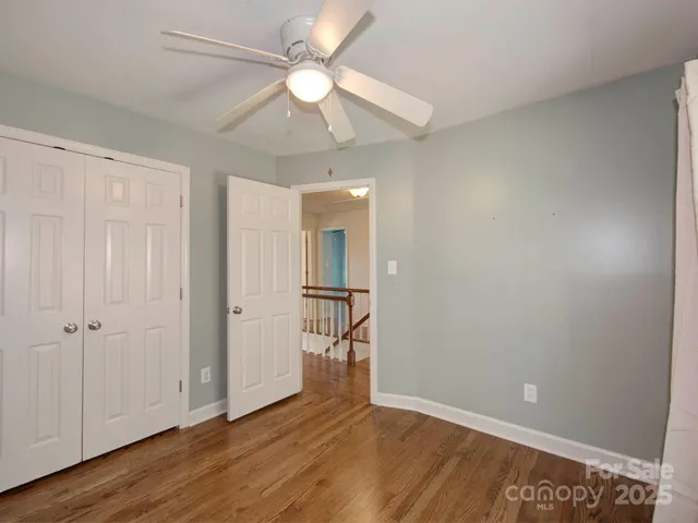 an empty room with wooden floor and a ceiling fan