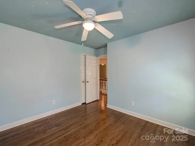 an empty room with wooden floor ceiling fan and a ceiling fan
