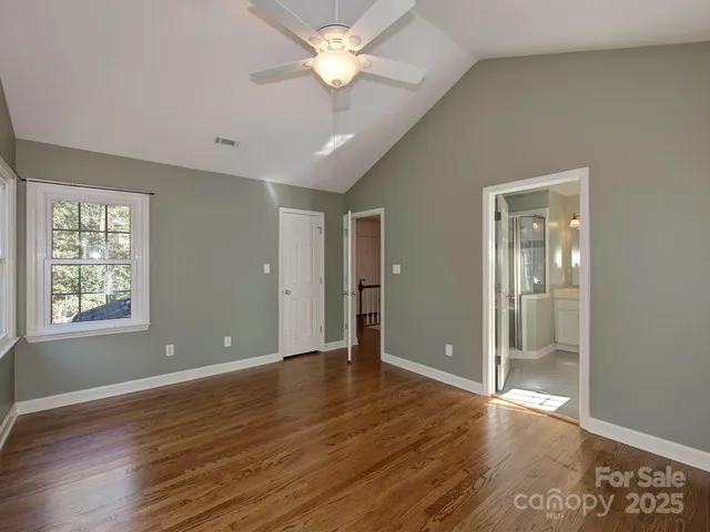 a view of an empty room with window and wooden floor
