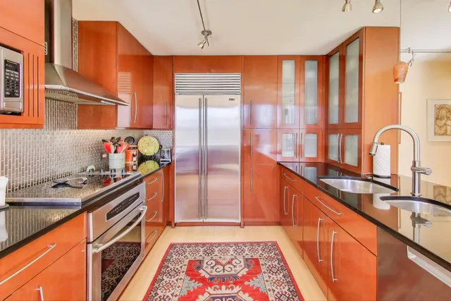a view of a kitchen with kitchen island a large window a sink and cabinets
