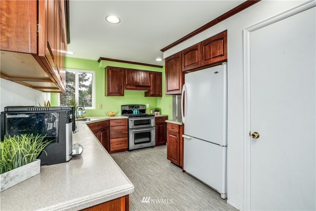527 224 Place Southeast Bothell, WA 98021 - Photo 5 of 23 a kitchen with stainless steel appliances granite countertop a refrigerator a stove a sink a counter space and cabinets