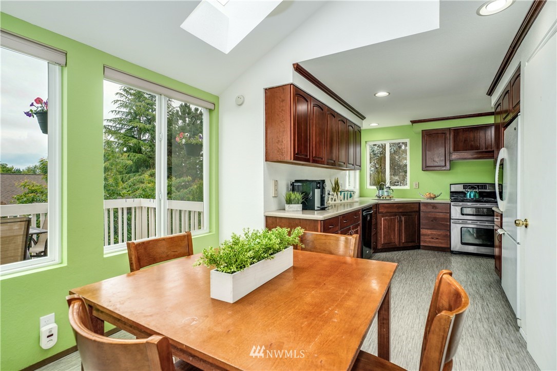 527 224 Place Southeast Bothell, WA 98021 - Photo 6 of 23 a kitchen with stainless steel appliances granite countertop a stove a refrigerator a sink dishwasher with a dining table and chair with wooden floor