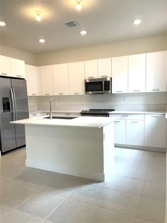 a kitchen with stainless steel appliances a sink a stove a microwave a counter top space and cabinets
