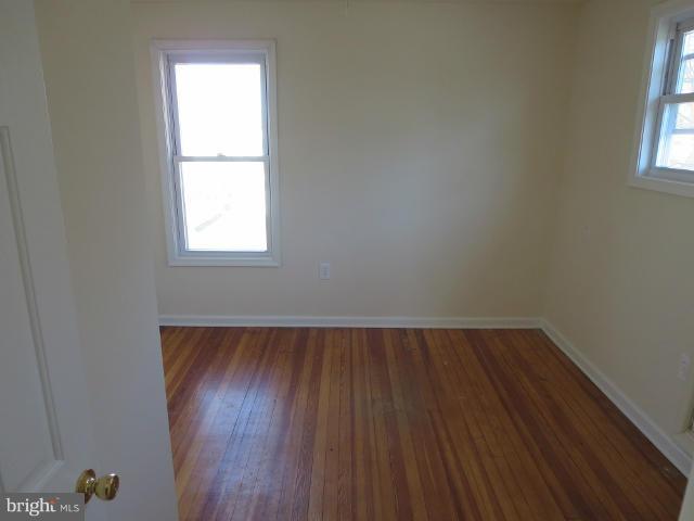7604 North Point Road Baltimore, MD 21219 - Photo 7 of 13 an empty room with wooden floor and windows