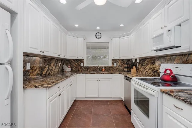 a kitchen with granite countertop white cabinets and white appliances