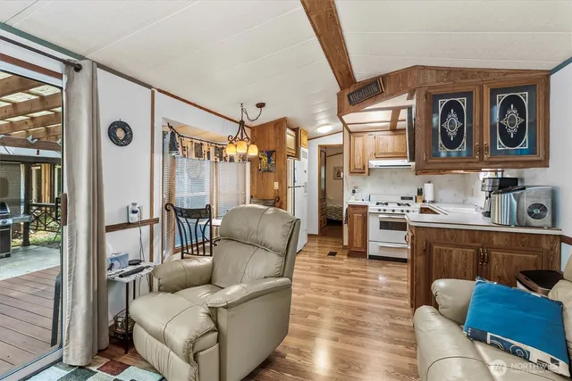 a living room with stainless steel appliances furniture and a kitchen view