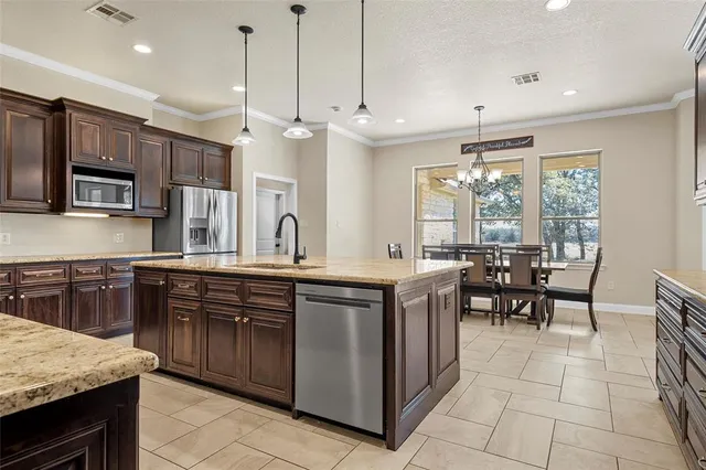 a kitchen with stainless steel appliances granite countertop a stove a sink a oven a dining table and chairs
