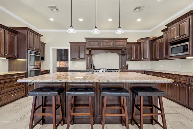 a kitchen with stainless steel appliances granite countertop a table chairs sink and wooden cabinets