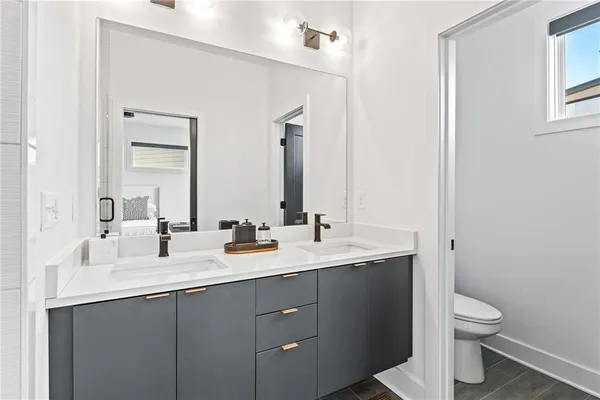 a bathroom with a double vanity sink toilet and mirror