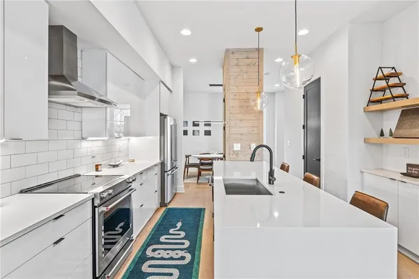 a large kitchen with stainless steel appliances a stove refrigerator a sink dishwasher with a dining table and chairs