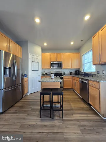 a kitchen with stainless steel appliances granite countertop a refrigerator a stove top oven and a sink