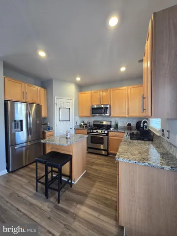 a kitchen with stainless steel appliances granite countertop a sink a stove a refrigerator cabinets and wooden floor