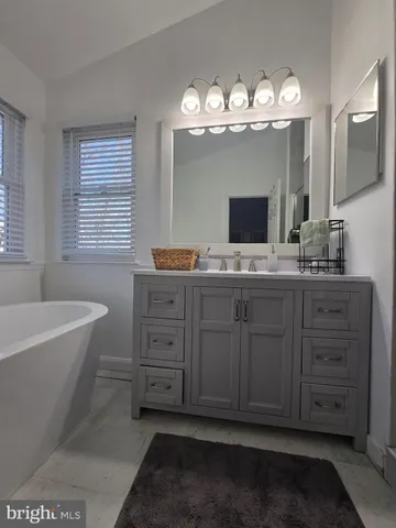 a spacious bathroom with a granite countertop sink a mirror and a bathtub
