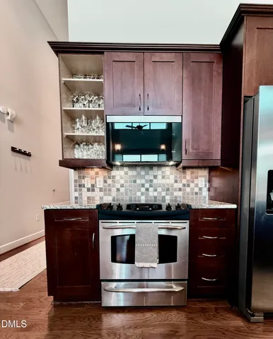 a kitchen with stainless steel appliances kitchen island granite countertop a stove a refrigerator and a sink