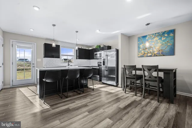 a kitchen with stainless steel appliances granite countertop a sink a stove a refrigerator and chairs