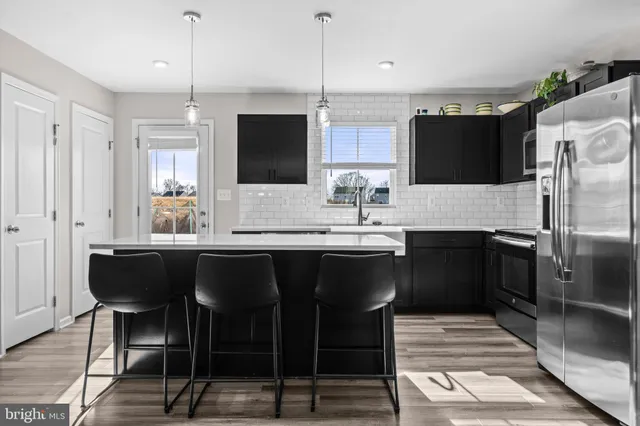 a kitchen with stainless steel appliances a sink dishwasher a stove top oven a refrigerator with island and chairs