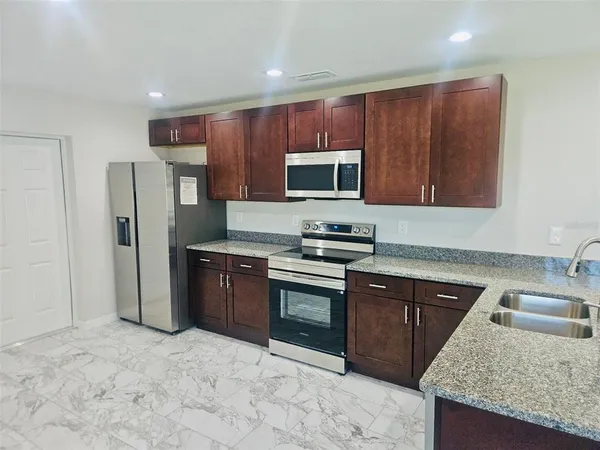 a kitchen with stainless steel appliances granite countertop a stove a sink dishwasher a refrigerator and a microwave oven