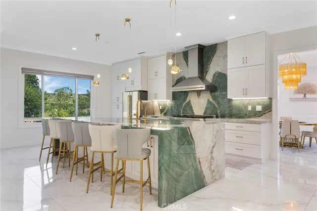 a kitchen with stainless steel appliances kitchen island granite countertop a dining table chairs and white cabinets