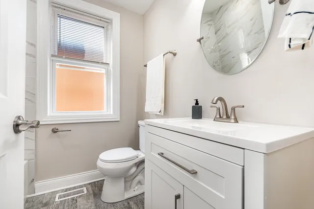 a bathroom with a toilet sink vanity and mirror