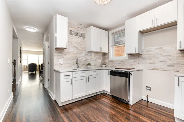 a kitchen with stainless steel appliances white cabinets and wooden floor