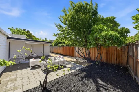 a white house with a tree and wooden fence
