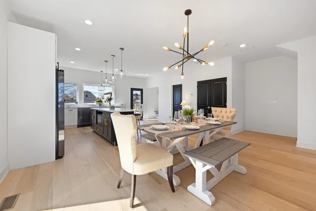 a dining room with wooden floor a chandelier a glass table and chairs