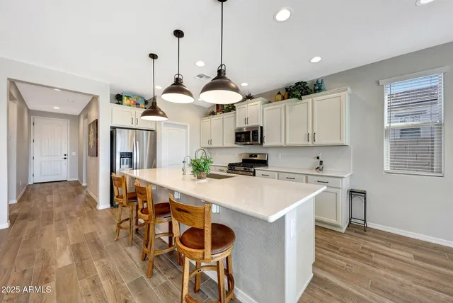 a kitchen with a dining table chairs stainless steel appliances and cabinets