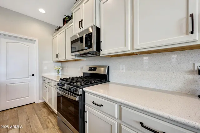 a kitchen with stainless steel appliances white cabinets and a stove top oven