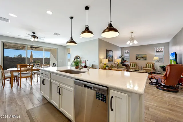 a kitchen with stainless steel appliances granite countertop a stove a refrigerator a dining table chairs and white cabinets