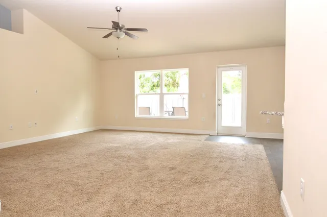 an empty room with windows and chandelier fan