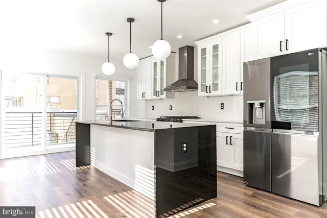 a kitchen with stainless steel appliances granite countertop a refrigerator a sink dishwasher a kitchen island with wooden cabinets and floor