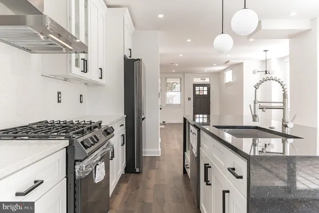a kitchen with granite countertop a sink a stove and refrigerator