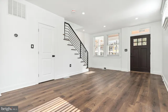 a view of an empty room with wooden floor and stairs