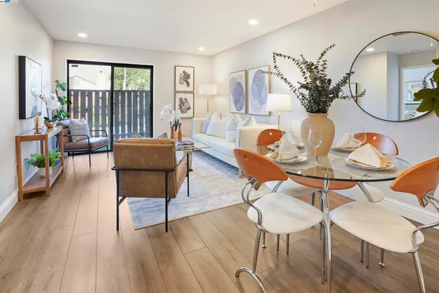 a living room with furniture a table wooden floor and a large window