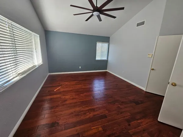 en empty room with wooden floor and windows