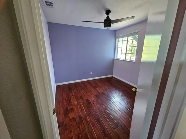 an empty room with wooden floor and windows
