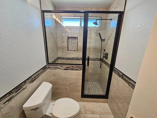 a bathroom with a granite countertop sink toilet and shower a mirror