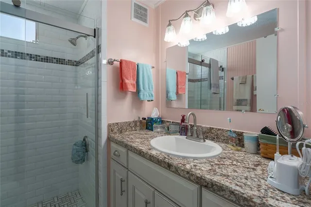 a bathroom with a granite countertop sink a mirror a vanity and shower