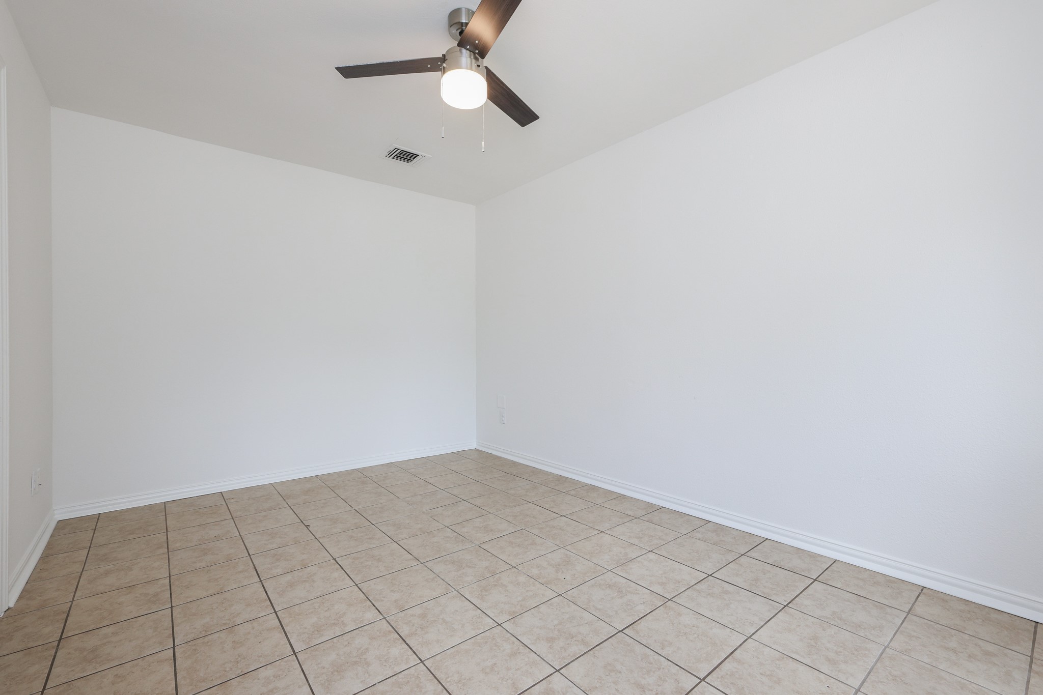 4823 Connorvale Road Houston, TX 77039 - Photo 5 of 26 This living room features clean white walls, a tiled floor, and a modern ceiling fan with light, creating a bright and airy space.