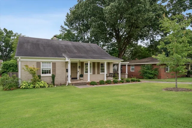 a front view of a house with a garden and trees