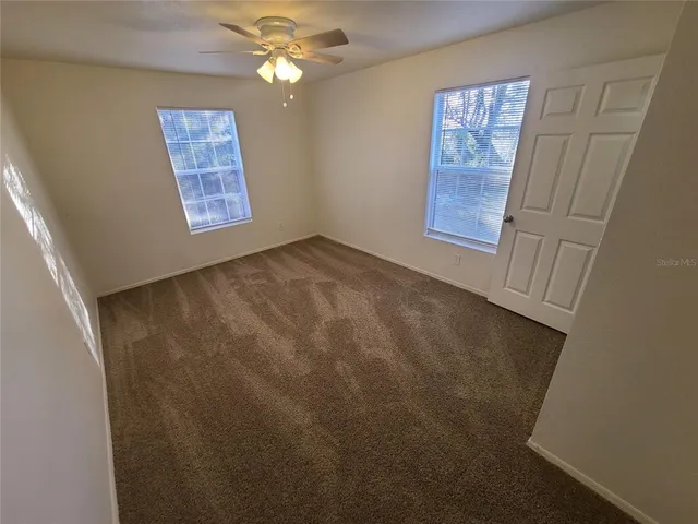 an empty room with fan and windows