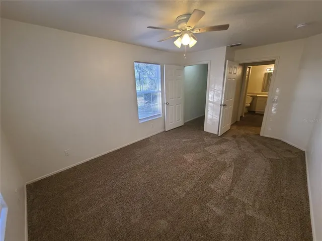 en empty room with windows and ceiling fan