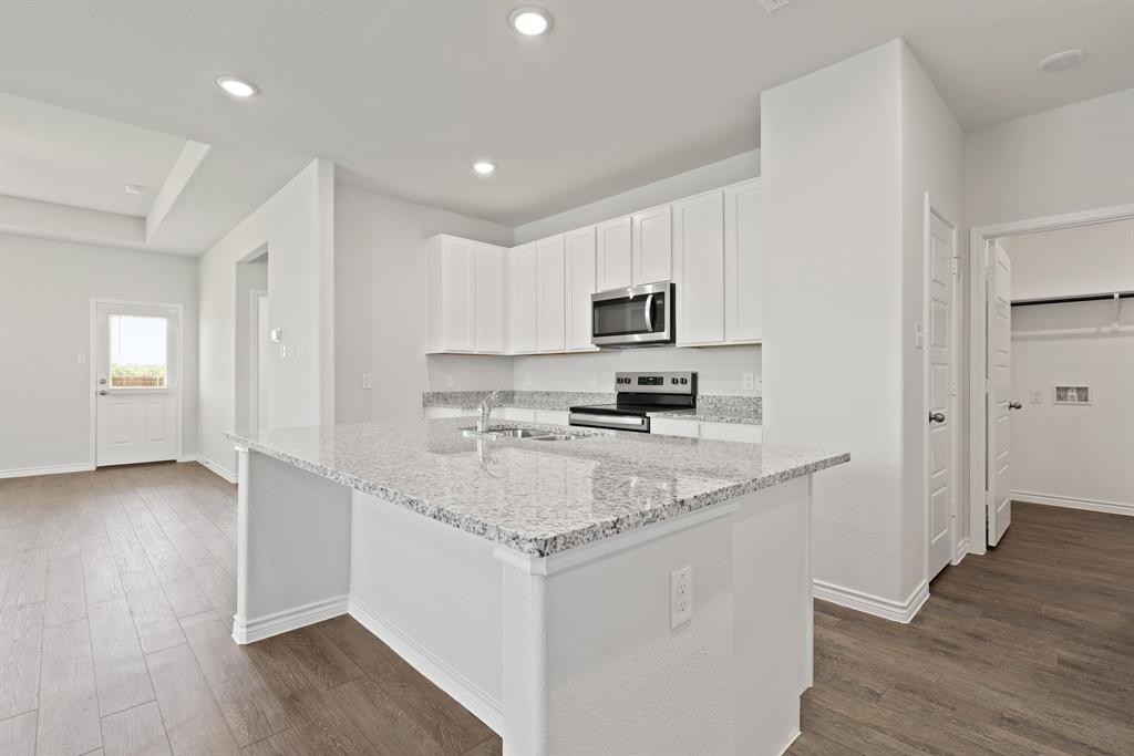 3112 Harmony Way Cleburne, TX 76031 - Photo 5 of 25 a kitchen with a sink a stove a microwave and cabinets