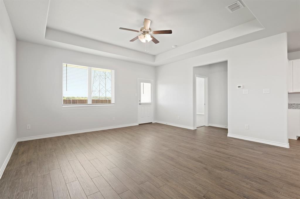 3112 Harmony Way Cleburne, TX 76031 - Photo 7 of 25 an empty room with wooden floor ceiling fan and windows