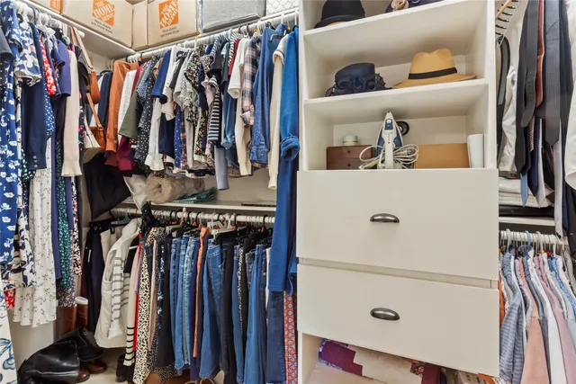 a view of walk in closet with clothes and shoes