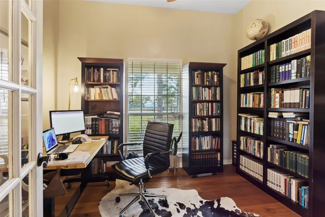 a view of a workspace with bookshelf and a window